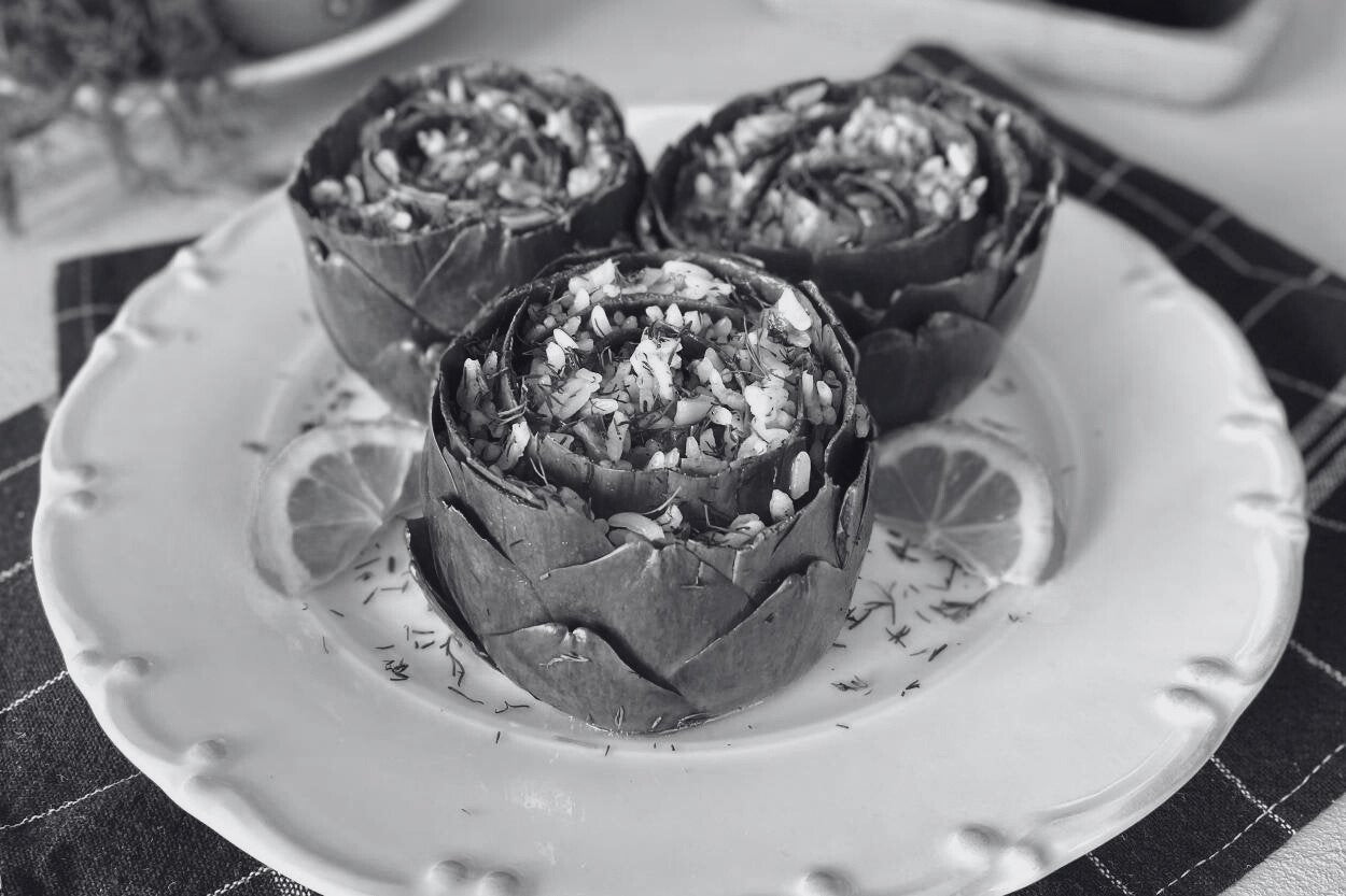 A beautifully plated stuffed artichoke, filled with a savory mixture of rice, herbs, and spices, ready to be enjoyed.