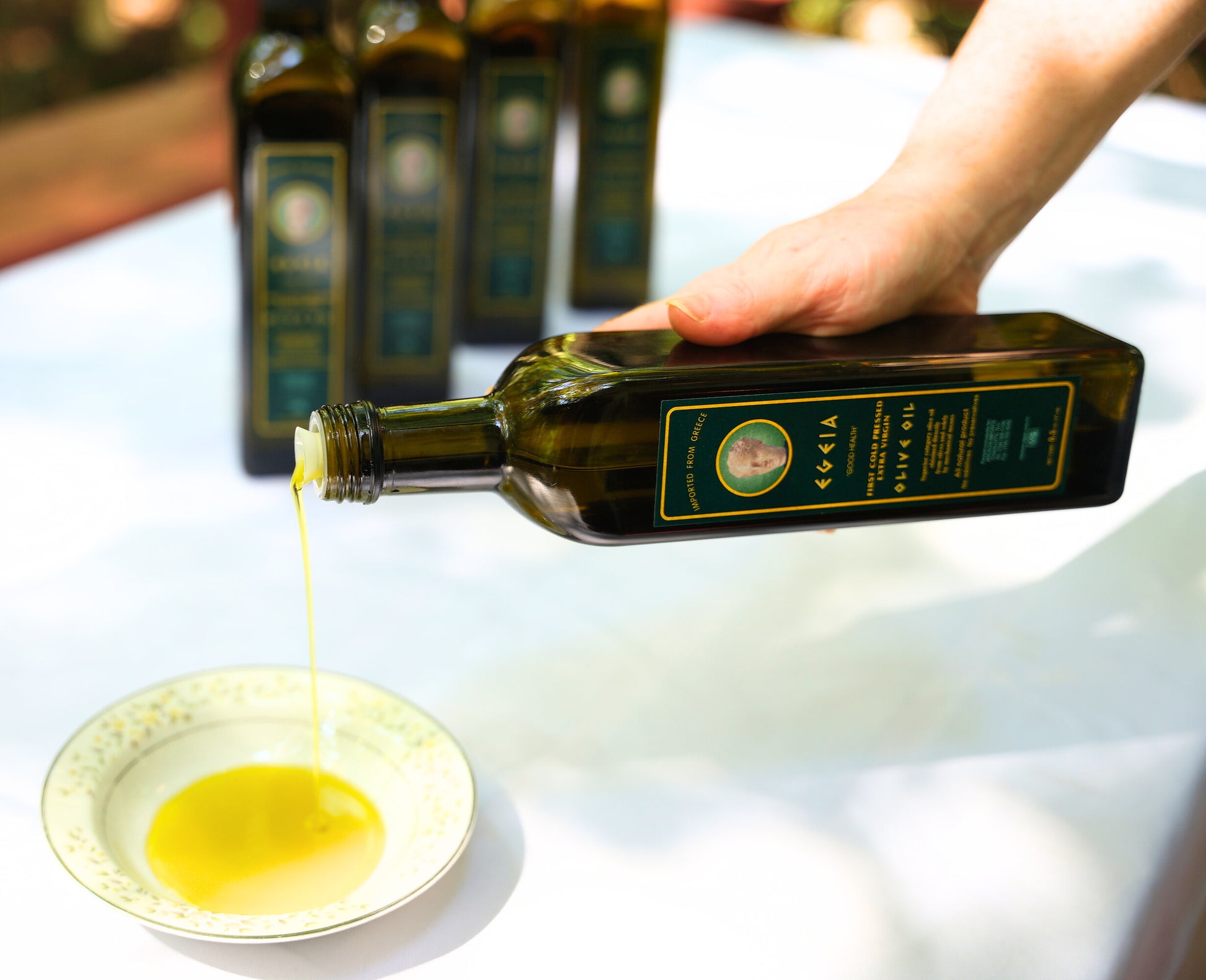 Pouring extra virgin olive oil from a glass bottle into a small bowl, showcasing its rich golden color and smooth texture.